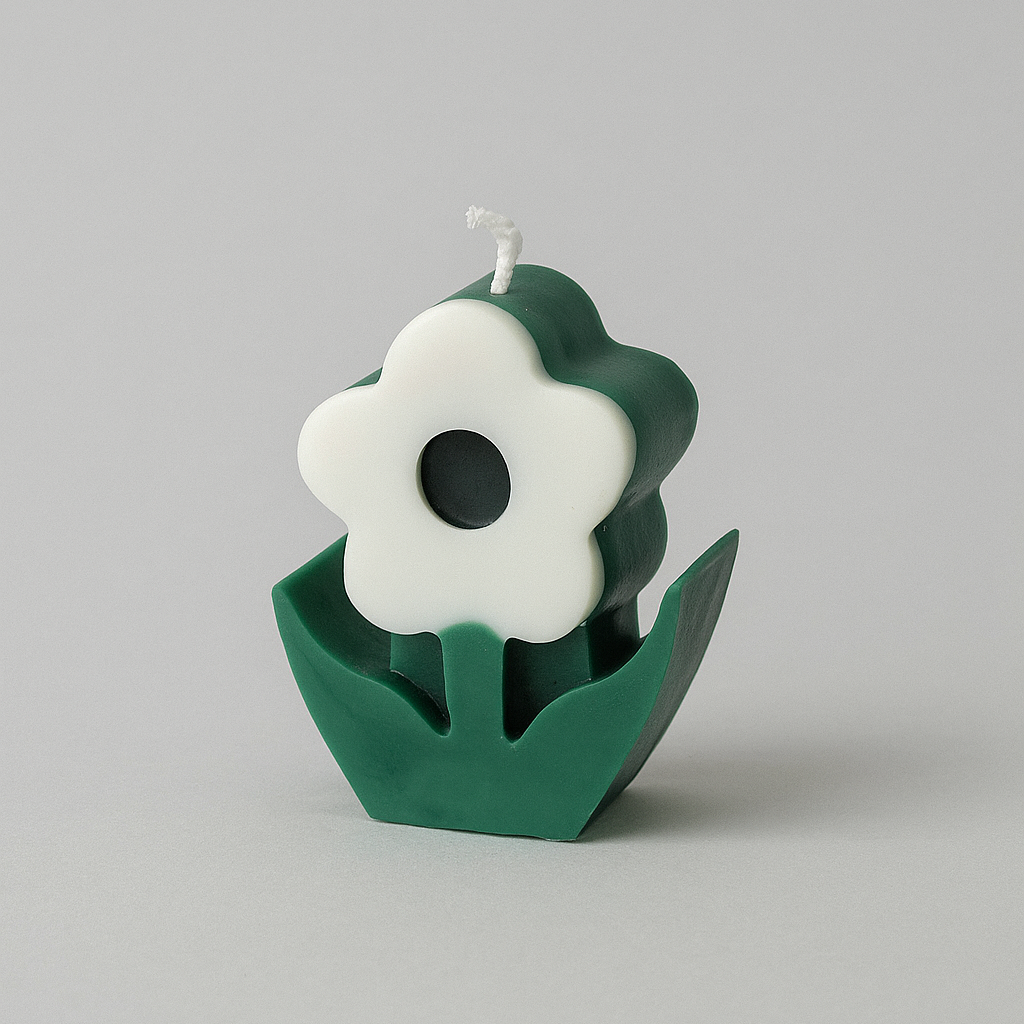 Candle shaped like a white flower in a green pot on a gray background